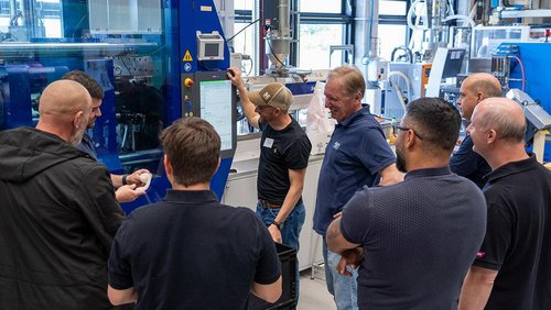 Team vor einer Spritzgießmaschine