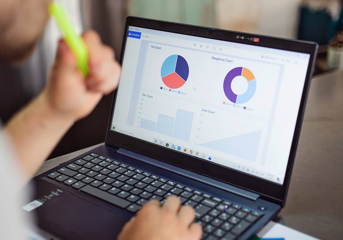 Mitarbeitende*r bei der Auswertung von Diagrammen am Laptop