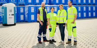 Employees in front of toilet cabins