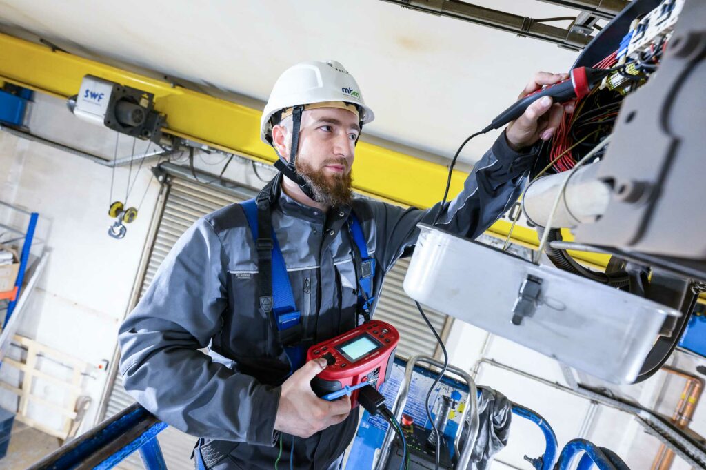 Servicetechniker prüft elektrische Steuerung eines Hallenkrans