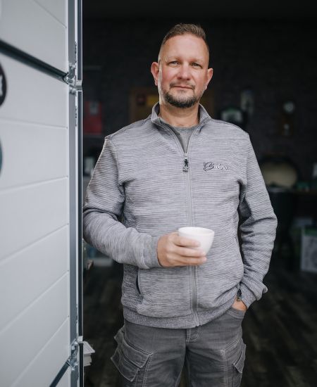 Employee with coffee cup in front of the workshop