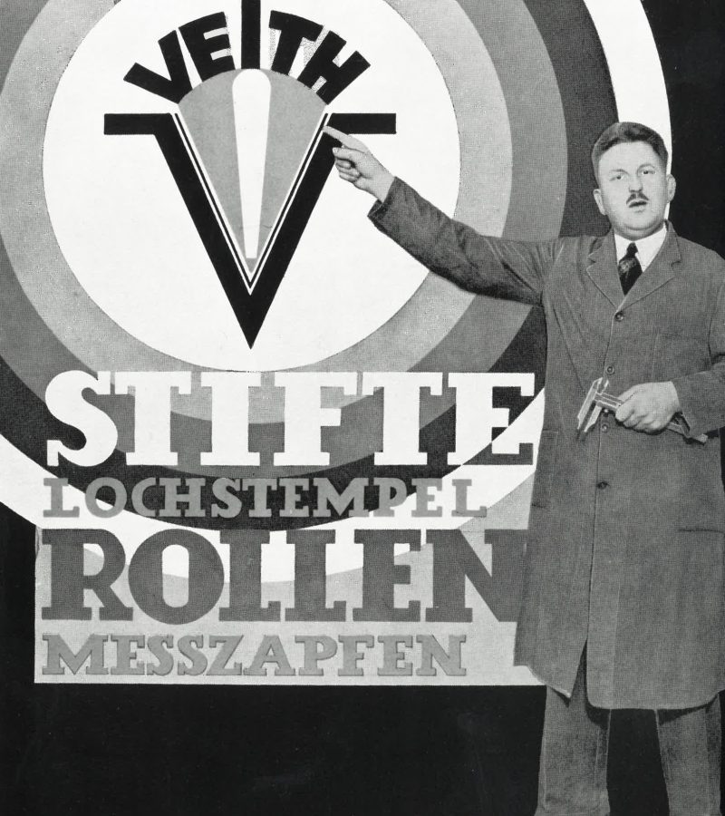 Mitarbeiter vor historischem Veith-Plakat